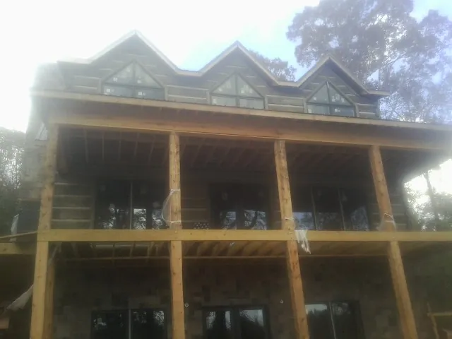 Dormers and porch framing on a large log home under construction — Roof Coating work by our crew in Scio
