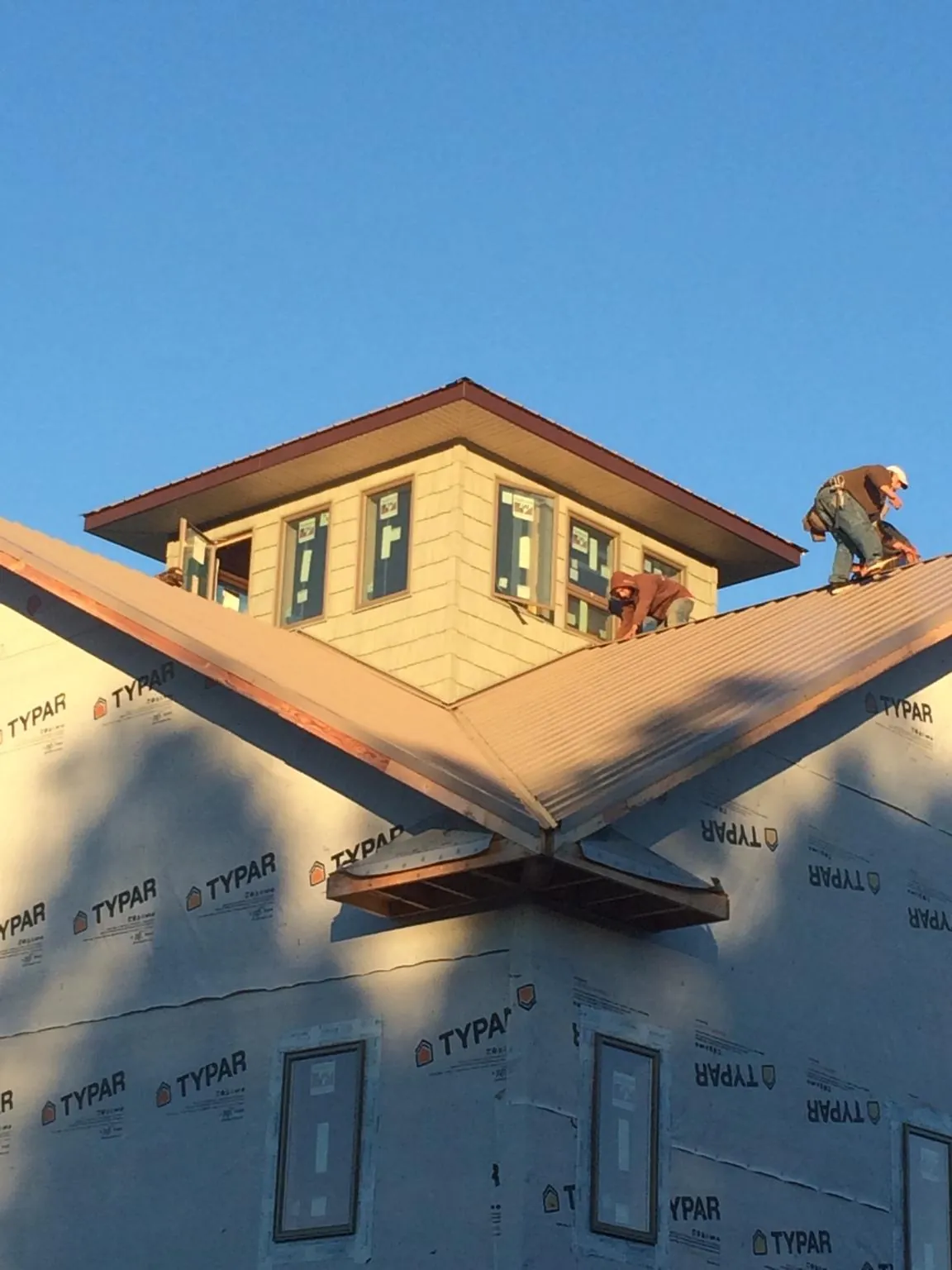Roofers working around a rooftop cupola on a new metal roof at sunset — Roof Waterproofing in Scio by Roofing Brothers
